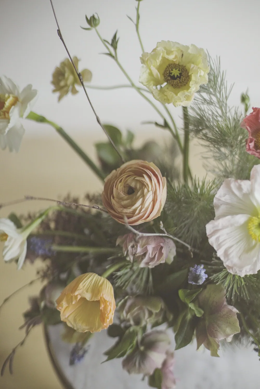 A green and white arrangement held in a ceramic vessel